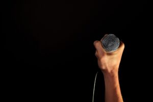 A black background with a hand holding a microphone
