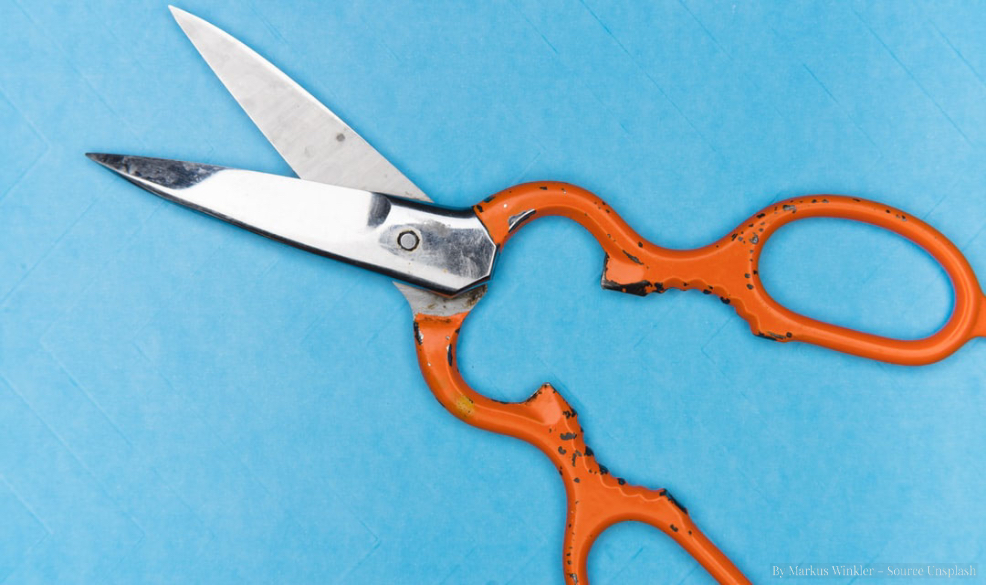 shiny scissors, with bright orange handles on a contrasting bright blue background